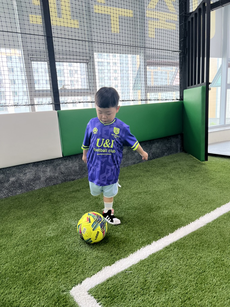 축구 연습 후 땀에 젖은 아빠와 아들이 잔디밭에 나란히 앉아, 아빠가 아들의 머리를 쓰다듬어주며 다정하게 대화하는 모습